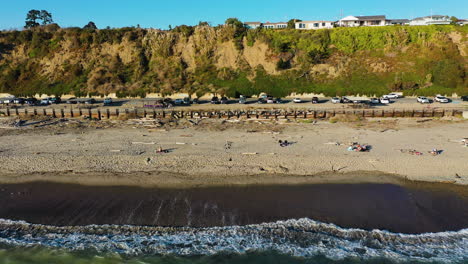 Toma-Aérea-De-Seguimiento-De-Personas-En-La-Playa-De-Aptos,-En-El-Soleado-Río-Del-Mar,-California,-EE.UU.