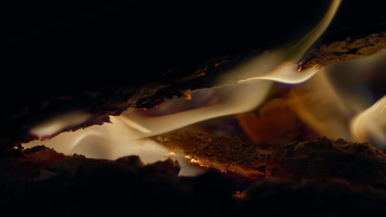 Slowmotion-optagelse af flammer og gløder i en pejs.