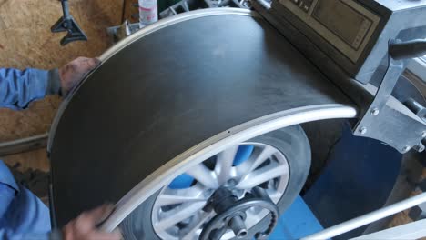 mechanic worker makes computer wheel balancing on special equipment machine tool in auto repair service, toned photo with motion effect