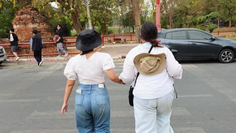 two women crossing road near ancient ruins