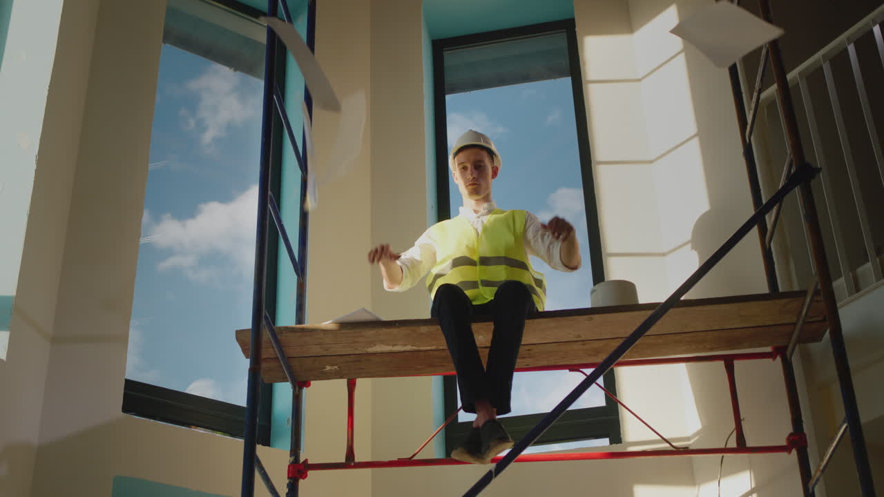 el malvado constructor rasga los documentos y se sienta en lo alto del andamio.