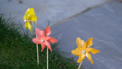 three coloured pinwheels spinning very fast in a back yard