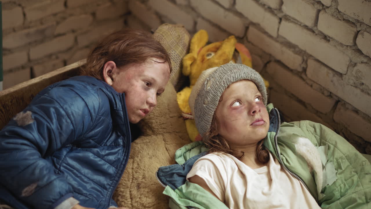 낡은 재킷을 입은 버려진 아이들이 벽돌 벽 근처에서 껴안은 봉제 인형에 기대어 지쳐 있고, 추운 도시 보호소 안에서 가난과 생존을 위한 힘겨운 싸움을 보여주고 있어요.