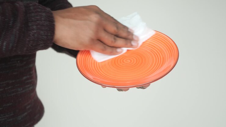 Cleaning an orange plate with a tissue