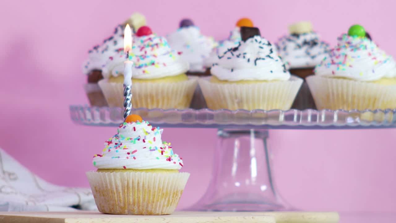 Burning birthday candle on cup cake served for birthday party on the table. Close up