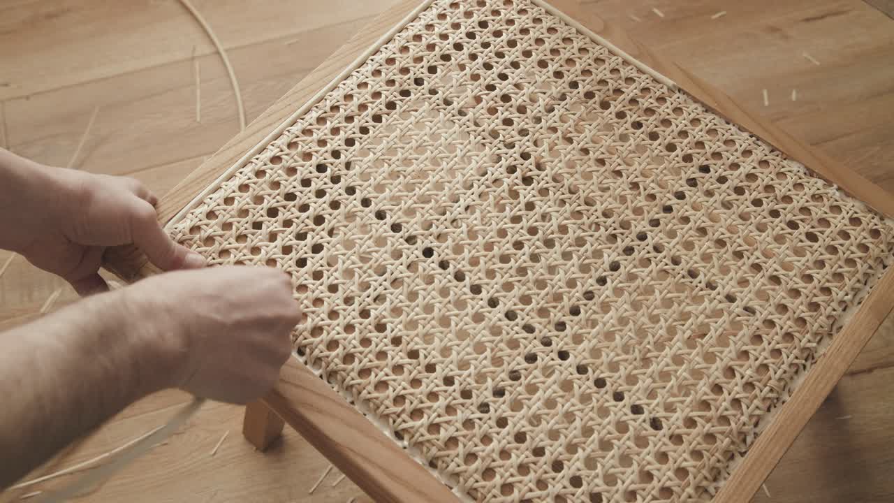 Rattan chair restoration, craftman is inserting the spline on the chair frame