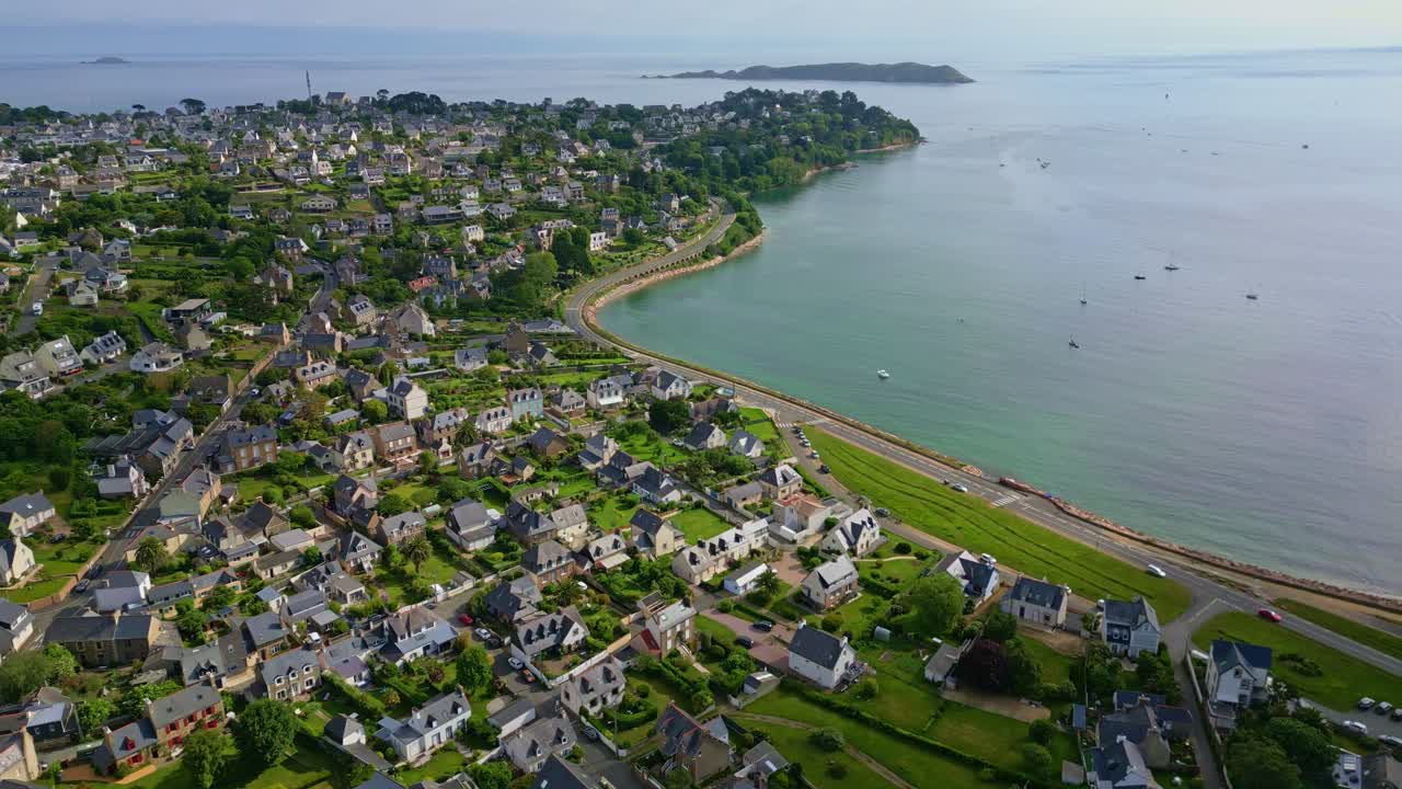 Aerial drone view over Perros-Guirec coastal town, panoramic road, and bay with boats, Brittany, France