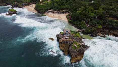 Vista-Aérea-De-Grandes-Olas-Golpea-La-Isla-De-Coral-En-La-Playa,-Disparo-De-Drones-En-órbita---Playa-Kukup,-Yogyakarta,-Indonesia