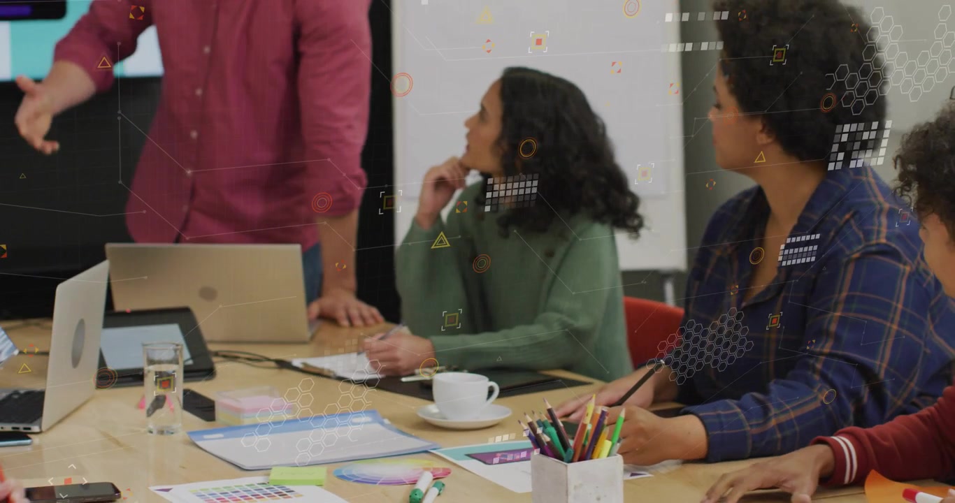Seated team arranging paper as presenter bringing devices and animating charts for business review