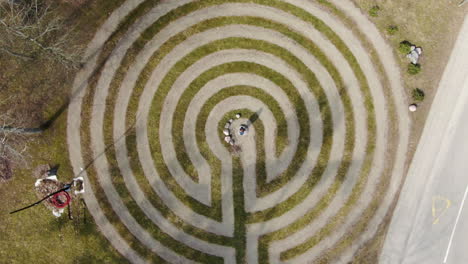 person standing in center of maze and walking out in birstonas, aerial ascend top down view