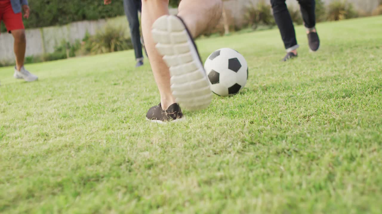 diversos amigos masculinos jugando al fútbol en el jardín en un día soleado