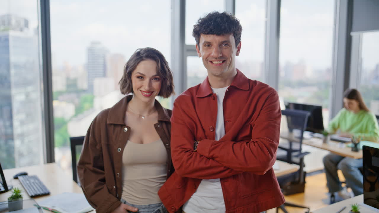 Dois membros de startup sorrindo para a câmera em close-up no escritório corporativo. Gestores felizes posando