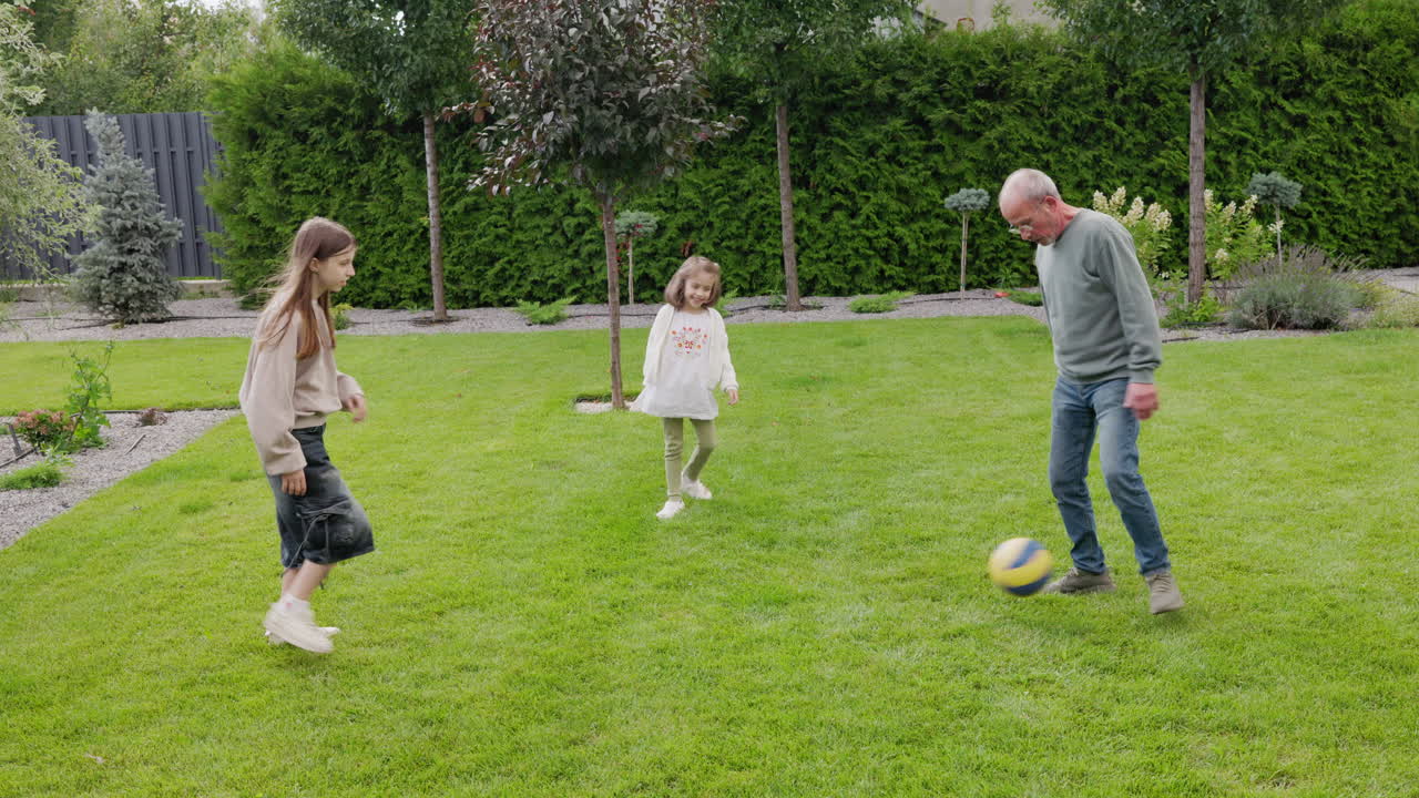 Active Grandfather Playing Football With Grandchildren In Backyard Garden Promoting Healthy Lifestyle