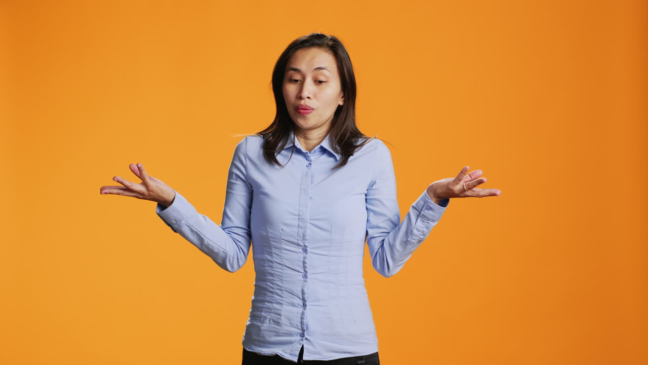 오렌지색 배경 위에서 어깨를 들어 올리는 의심스러운 모델