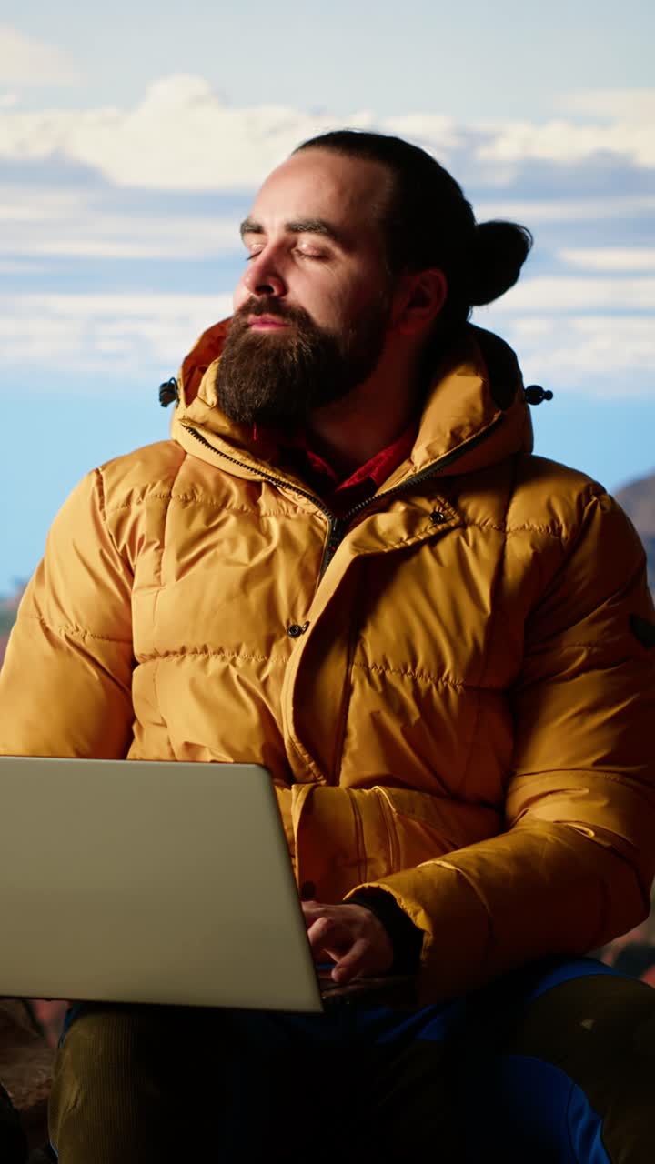 Uomo barbuto che lavora al laptop in un suggestivo ambiente all'aperto