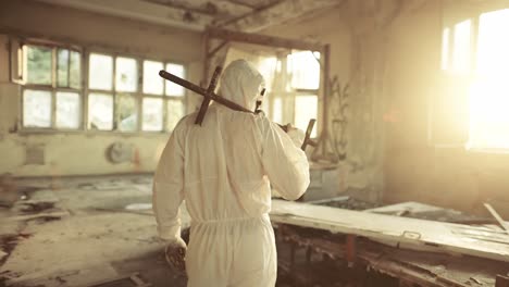 worker in protective suit inside the ruined building exploring abandoned area, rear view