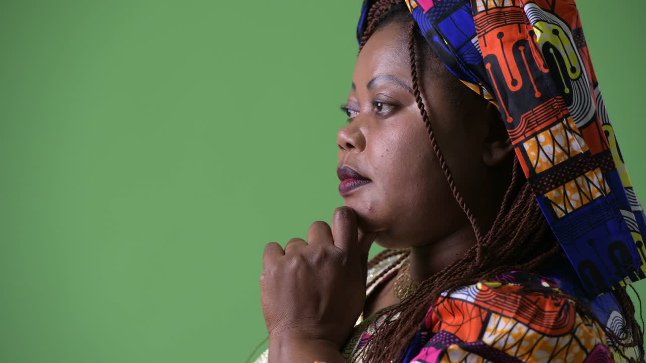 Overweight beautiful African woman wearing traditional clothing against green background