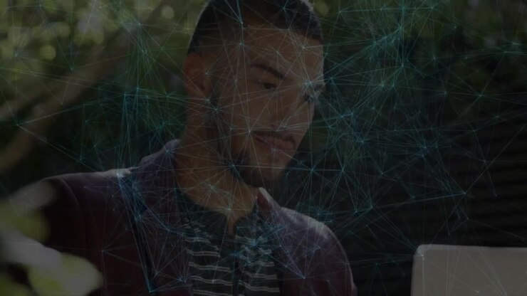 Man leaning into laptop scanning text causing network graphic receding and enabling technology work