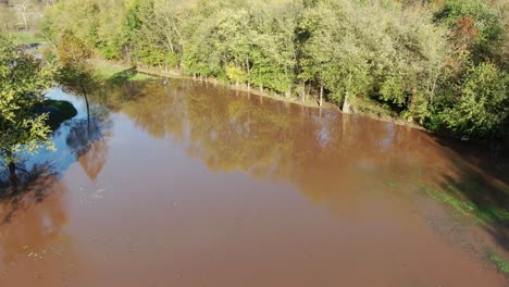 rising aerial, tilt down reveals flooded park in autumn in pennsylvania