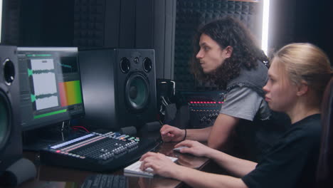 female audio engineer and musician create song in music recording room. computer screen showing daw software interface with sound track. modern equipment in sound recording studio. music production.