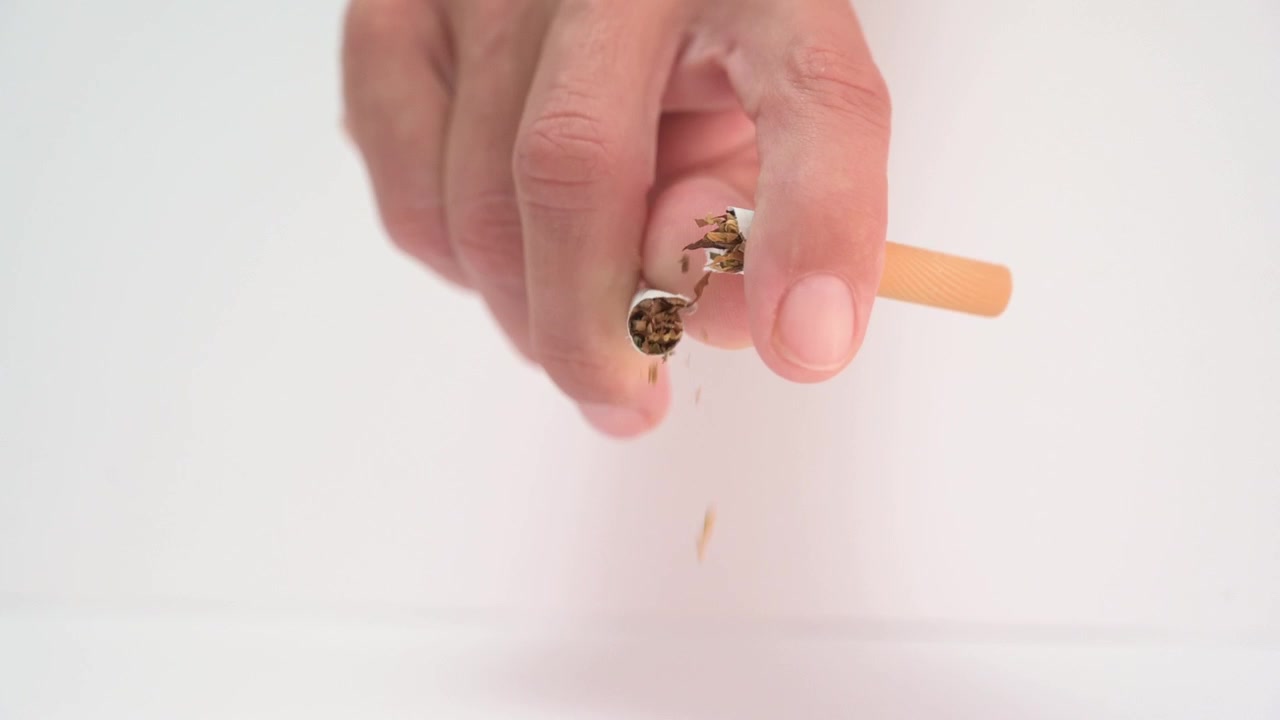 Mão quebrando um cigarro isolada em um fundo branco para o Dia Mundial Sem Tabaco
