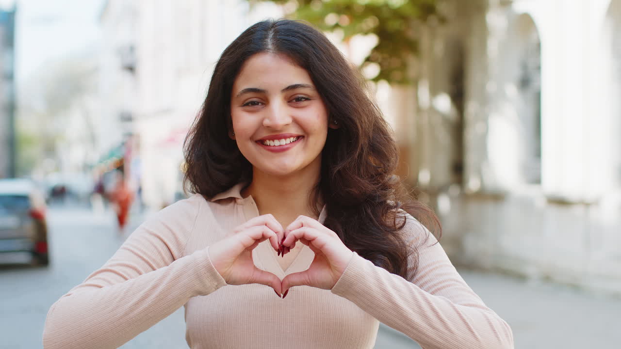 la mujer india hace un símbolo de amor, mostrando el signo del corazón a la cámara, expresando sentimientos positivos románticos