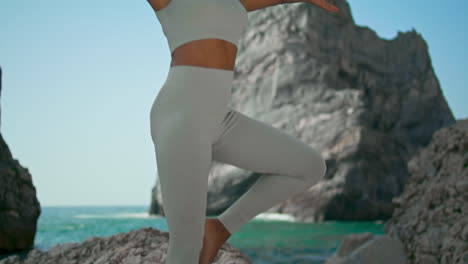 niña practicando asana árbol de pie rocosa playa de ursa verticalmente. mujer postura de yoga