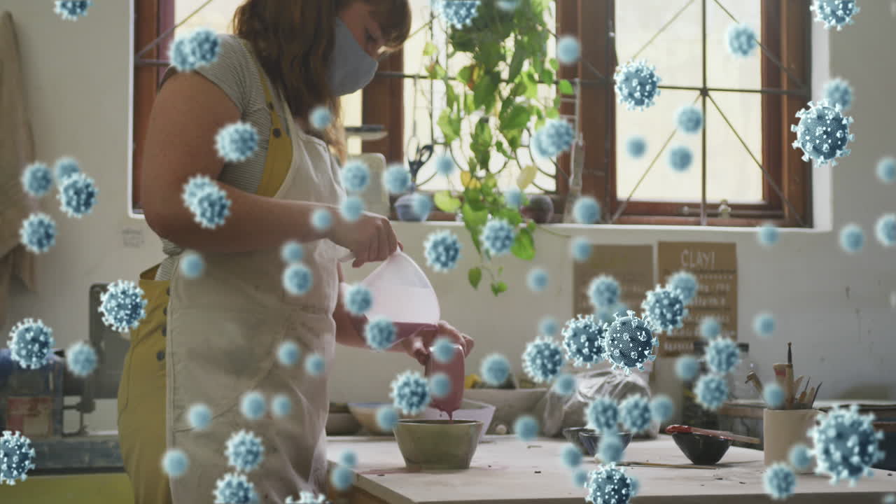 animación de células de covid-19 sobre una mujer que trabaja en un estudio de cerámica con una máscara facial