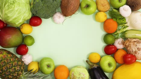 fresh fruits and vegetables make healthy food frame on light green theme. stop motion flat lay