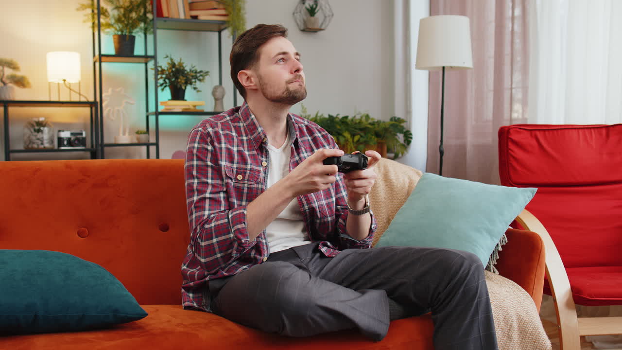 Man using joystick controller playing video console television game fun enjoying at home room sofa