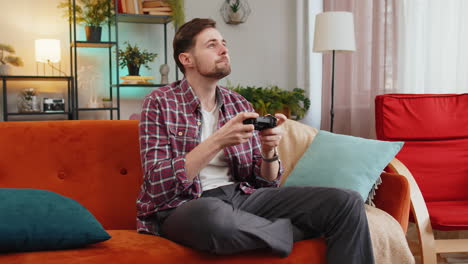 Man-using-joystick-controller-playing-video-console-television-game-fun-enjoying-at-home-room-sofa