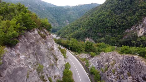 cinematic drone shot over road and river and nature in italian mountains