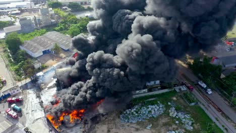 volando vicino a un enorme incendio devastante mentre consuma un grande magazzino commerciale creando un'enorme nuvola di fumo nero durante il giorno