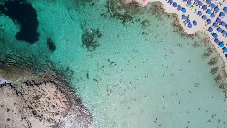 Aerial-overhead-footage-of-people-bathing-at-a-shallow-sandy-beach