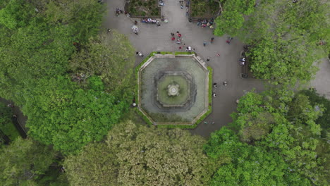 top down aerial footage of a fountain with tourists walking around in the main square in antigua, guatemala