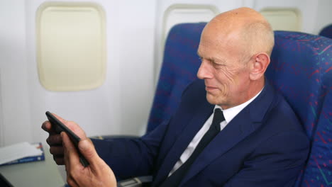 a happy mature business man on an airplane watching a movie