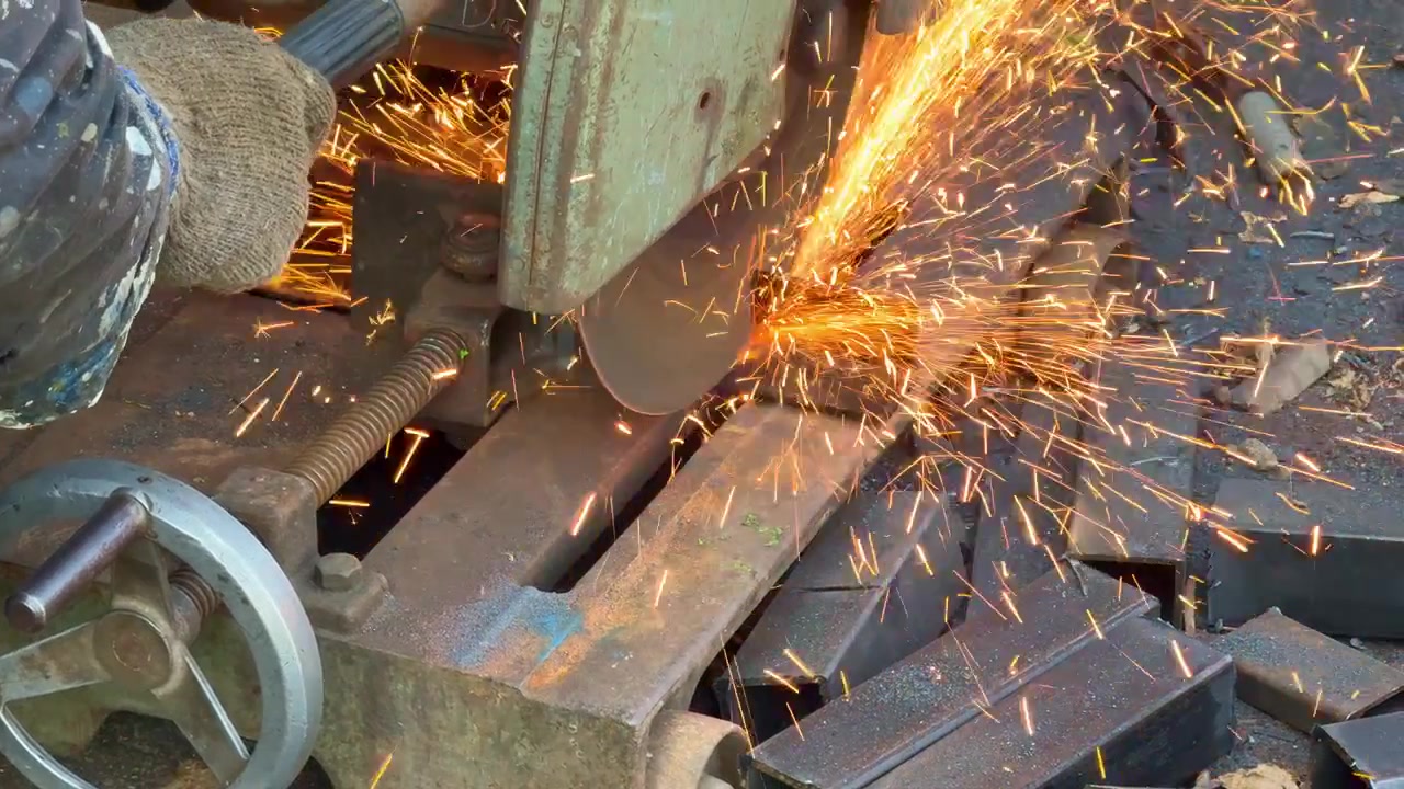 Smerigliatrice che taglia un tubo d'acciaio, scintille che volano in officina. Filmato ravvicinato che illustra la fabbricazione industriale, la lavorazione dei metalli e il concetto di costruzione.