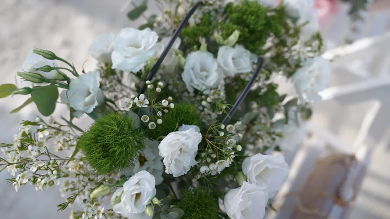 A lovely arrangement of white flowers with green accents is showcased in an elegant outdoor location, perfect for weddings or celebrations, capturing a moment of beauty and tranquility