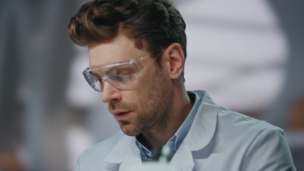 Scientist wearing safety glasses investigate medicines in laboratory close up.