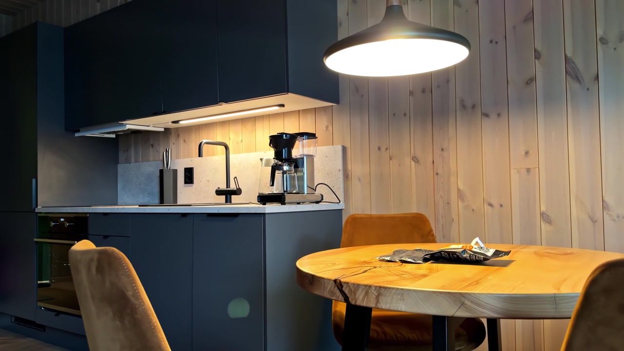 Cucina e zona pranzo moderne con pareti rivestite in legno e un'atmosfera di illuminazione calda