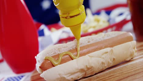 hot dog with mustard sauce on wooden board