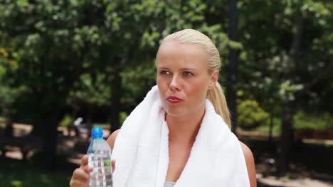 a woman takes a drink of water and then wipes her forehead