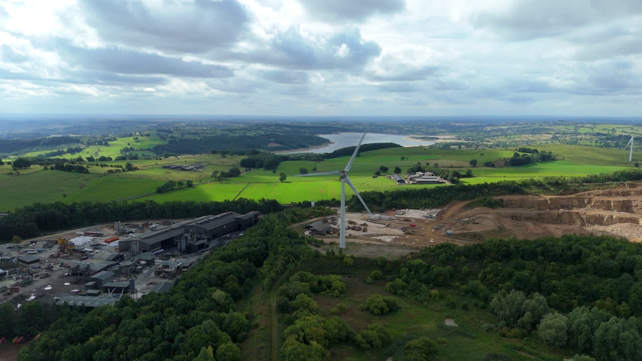 Aerial drone perspective of windmills, factories, and quarry in rural green landscape Derbyshire Dales United Kingdom