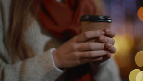 girl hands holding paper cup outdoor. unknown woman standing with coffee outside