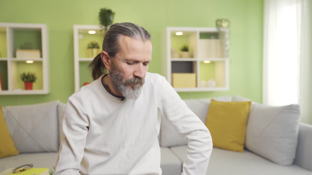 Sad and depressed old man thoughtful at home alone.