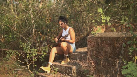 hispanic young teenager playing acoustic guitar in summer countryside