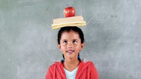 Schulmädchen-Mit-Einem-Apfel-Und-Einem-Buch-Auf-Dem-Kopf-Im-Klassenzimmer