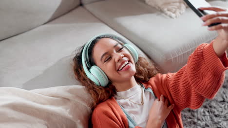 woman taking a selfie while listening to music on a couch