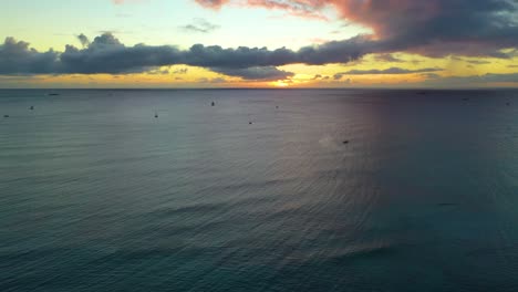 veleros que viajan a través del océano pacífico en vacaciones turísticas en una puesta de sol hawaiana, navegando las olas frente a la costa de la playa de waikiki en honolulu - sobrevuelo de drones aéreos