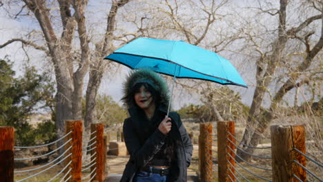 una bella mujer abriendo un paraguas azul y sonriendo alegremente durante una tormenta de lluvia para protegerse del mal tiempo a cámara lenta